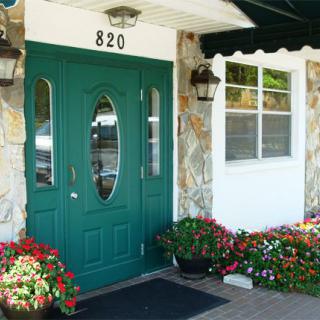 A building entrance with a green door, stone walls, and decorative flowers.