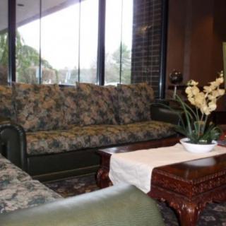A cozy living room with floral-patterned sofas, a wooden coffee table, and a plant by the window.