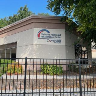 A building with a sign reading 'California Driver and Safety Education Center' behind a fence and surrounded by trees.