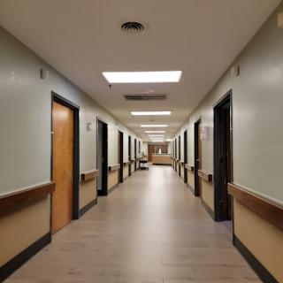 A long, empty hallway in a healthcare facility with doors on either side.
