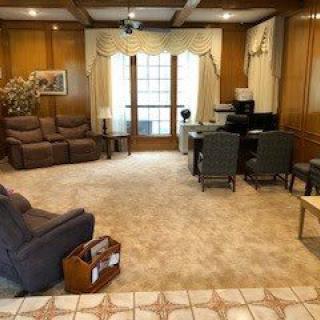 A cozy living room with wood paneling, featuring a sofa, chairs, and a desk.