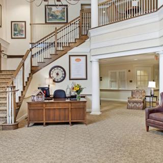 A spacious lobby area featuring a wooden staircase, reception desk, and comfortable seating.