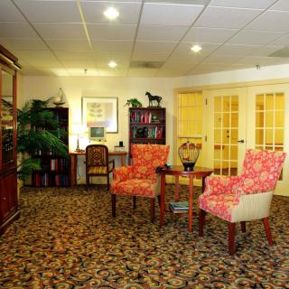 A cozy office waiting room with patterned chairs, bookshelves, and a carpeted floor.
