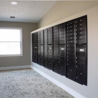 A mailroom with a wall of black mailboxes in an apartment building.