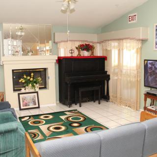 A cozy living room with a piano, fireplace, and television.