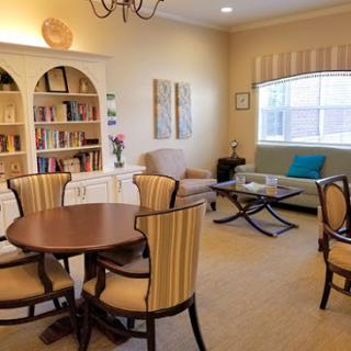 A cozy living room setting featuring a round dining table, stylish chairs, and a bookshelf filled with books.