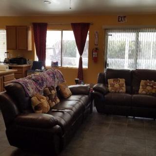 A cozy living room with leather sofas and a view into the kitchen.