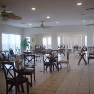 A spacious, well-lit dining area with empty tables and chairs on a tiled floor.