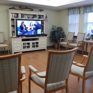 A cozy living room with chairs arranged in front of a large television.