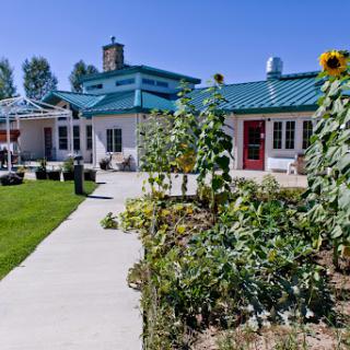 A beautiful building surrounded by a vibrant garden featuring sunflowers and well-maintained pathways.