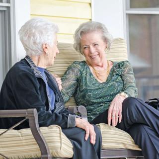 Two elderly women enjoying a conversation on a porch.