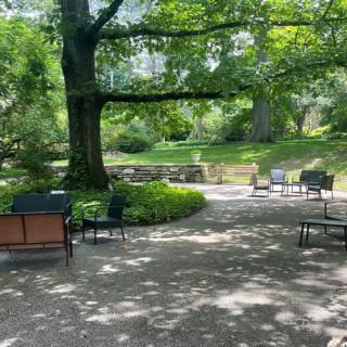 A peaceful park scene with chairs and abundant greenery.