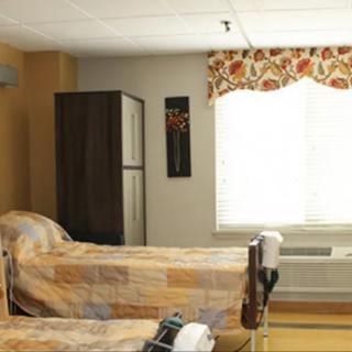 A hospital room with two beds and a window with floral curtains.