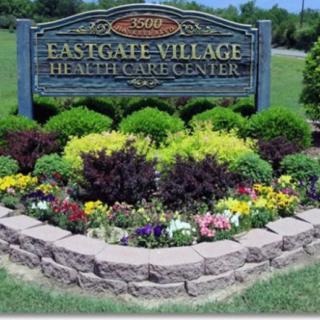 Entrance sign for Eastgate Village Healthcare Center surrounded by landscaped flowers and plants.