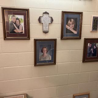 A collection of framed family photographs and a religious cross displayed on a wall.