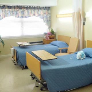 A hospital room with two neatly arranged patient beds and bedside tables.