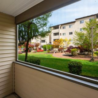 A view from a balcony overlooking a garden and apartment building.