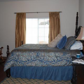 A cozy bedroom with a large bed, decorative pillows, and a window with curtains.