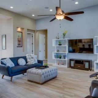 A modern living room with comfortable seating and a TV, featuring a ceiling fan and stylish decor.