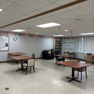 A spacious room configured with several tables and chairs, suitable for meetings or activities.