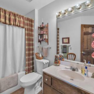 A cozy bathroom with a sink, mirror, and shower curtain, featuring warm decor and vanity lighting.