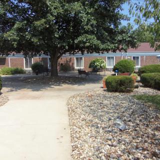 A serene outdoor space featuring a pathway winding through well-maintained gardens and shaded by trees.