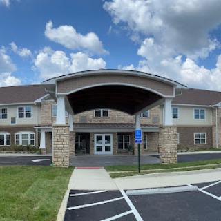A modern healthcare facility entrance under a partly cloudy sky.
