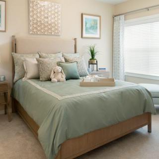 A cozy bedroom featuring a neatly made bed with decorative pillows, soft lighting, and elegant decor.