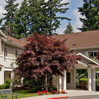 A residential building with a manicured landscape and trees surrounding the entrance.