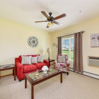A cozy living room with a red sofa, armchair, and a coffee table beneath a ceiling fan.
