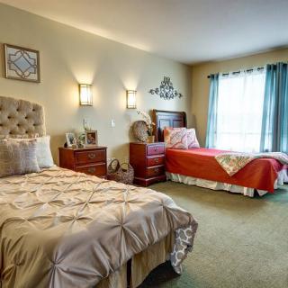 A cozy bedroom with two neatly made beds, warm lighting, and tasteful decorations.