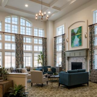 A spacious living room with high ceilings, large windows, and modern furnishings.
