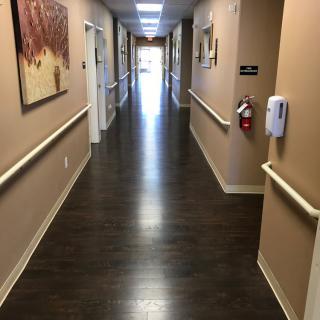 A long, well-lit indoor hallway with wooden floors and handrails along the walls.