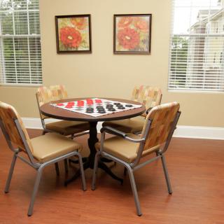 A cozy room with a round table and four chairs, featuring a checkers board setup.