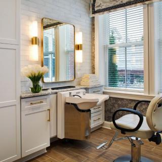 A modern hair salon interior featuring a vanity, mirror, and stylish lighting.