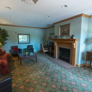 A cozy living room with a fireplace, sofas, and chairs arranged on a patterned carpet.