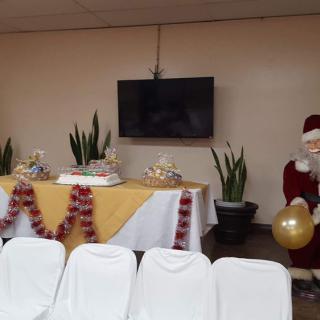 A festive indoor setting with a decorated table featuring cakes and an inflatable Santa Claus.