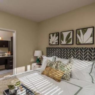 A well-decorated bedroom with a patterned headboard, framed leaf artwork, and cozy bedding.