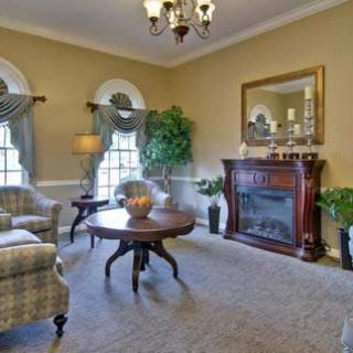 A traditional living room with classic furniture, featuring a fireplace and large windows.