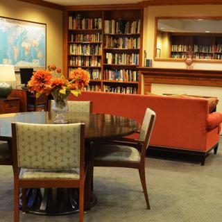 A cozy library room with bookshelves, a round table, and comfortable seating.