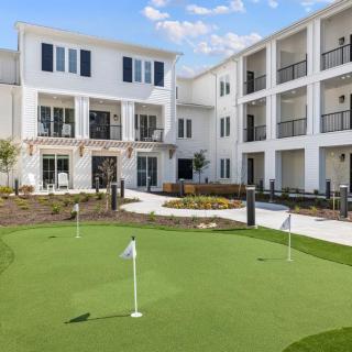 A modern apartment complex featuring a putting green and well-maintained outdoor landscaping.