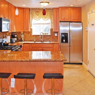 A modern kitchen featuring granite countertops, wood cabinets, and stainless steel appliances.
