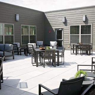 A modern outdoor patio featuring several tables and comfortable seating arrangements.