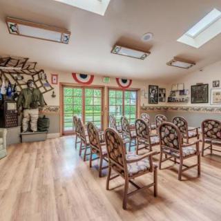 A well-lit presentation room with neatly arranged chairs, decorated walls, and natural wooden flooring.