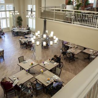 A spacious dining hall with elegantly arranged tables and a large chandelier.