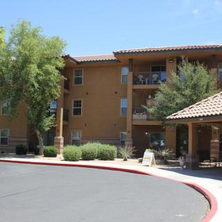 A view of an apartment building with a landscaped entrance area.