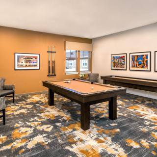 A modern game room featuring a pool table, art-adorned walls, and a comfortable seating area.