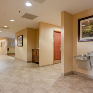 A well-lit hotel hallway featuring a water fountain and artwork on the walls.