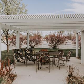 A beautiful outdoor patio with a pergola and decorative metal furniture.