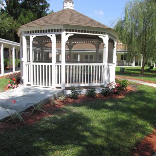 A charming white gazebo in a landscaped garden setting.